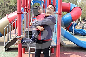 Divorced dad plays with his brunette latina daughter in playground park spins and hugs spend fun time photo