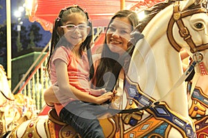 Divorced single mom and 5 year old brunette Latina daughter spend fun time on amusement park carousel