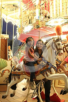 Divorced single mom and 5 year old brunette Latina daughter spend fun time on amusement park carousel