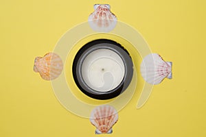 Diwali candle surrounded by four sea shells against light yellow background