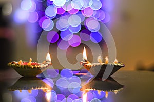 Diwali earthen lamps on the foreground of beautifully illuminated lights