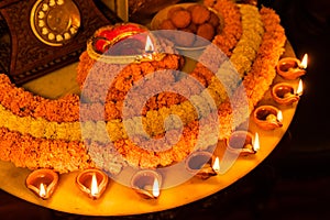 Diwali glowing Diya and flowers arranged in circular shape forming a design with copy space, selective focus