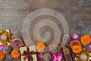 Diwali holiday concept with sweet traditional dessert, gift box and decorations on dark background. Top view, flat lay