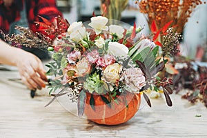 DIY autumn flower arrangement bouquet in pumpkin, florist at the work, floristry studio