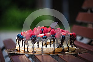DIY cake with berries and chocolate on a wooden bench