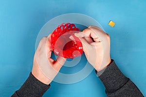 Diy Easter egg basket made of red plastic cup decorated with artificial flowers on blue background