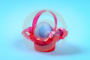 Diy Easter egg basket made of red plastic cup decorated with artificial flowers on blue background