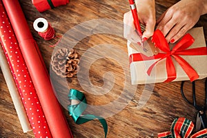 DIY Gift Wrapping. Woman filling out christmas gift tag on rustic wooden table. Overhead view of christmas wrapping.