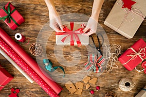 DIY Gift Wrapping. Woman wrapping beautiful christmas gifts on rustic wooden table. Overhead view of christmas wrapping.