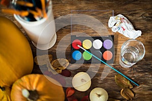 DIY Halloween concept. Art and craft, decorating Halloween pumpkins. Color pallete, paintbrush and pumpkins on a table.