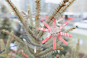 DIY handmade decoration made of craft sticks painted red on Christmas tree