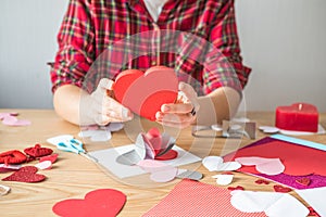 DIY holiday card with red paper heart, symbol of love. Girl  makes Mother`s Day, Valentine`s Day, greeting card. Hobby,  art