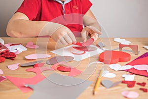 DIY holiday card with red paper heart, symbol of love. Kid boy makes Mother`s Day, Valentine`s Day, greeting card. Hobby, childr