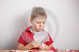 DIY holiday card with red paper heart, symbol of love. Kid boy makes Mother`s Day, Valentine`s Day, greeting card. Hobby, childr