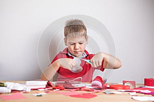 DIY holiday card with red paper heart, symbol of love. Kid boy makes Mother`s Day, Valentine`s Day, greeting card. Hobby, childr