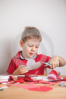 DIY holiday card with red paper heart, symbol of love. Kid boy makes Mother`s Day, Valentine`s Day, greeting card. Hobby, childr