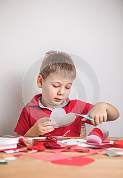 DIY holiday card with red paper heart, symbol of love. Kid boy makes Mother`s Day, Valentine`s Day, greeting card. Hobby, childr