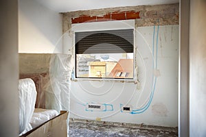 DIY, house indoor improvements in a messy room construction. Renovated windows, blue lines to electrical installation and wall
