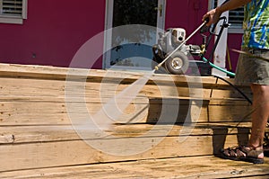 DIY man pressure washing wooden deck stairs