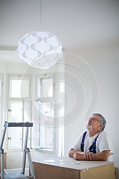 Senior landlord hanging a new light in a rental appartement photo