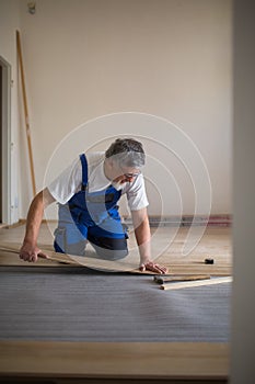 Senior landlord lying parquet floor board/laminate flooring in a rental appartement photo
