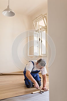 Senior landlord lying parquet floor board/laminate flooring in a rental appartement photo