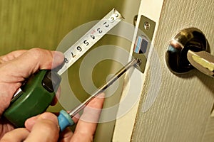 DIY repair, worker installing door lock using hand screwdriver