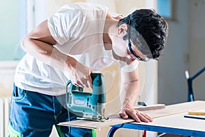 DIY worker cutting wooden panel with jig saw