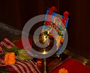 A diya or lamp is illuminated in front of goddess Laxm