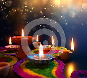 Diya lamps lit on colorful rangoli