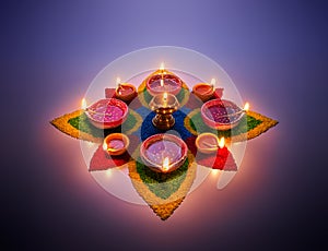 Diya lamps lit on colorful rangoli