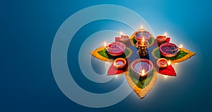 Diya lamps lit on colorful rangoli