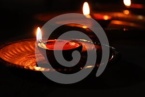 Diyas or earthen lamps lit and placed in a line in copper plates during the festival of Diwali in India with background and copy s