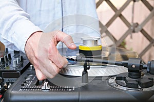 The DJ adjusts the needle on the turntable. Hand of a male DJ in a blue shirt