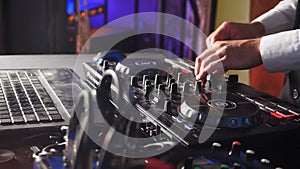 DJ behind console, on stage, mixing tracks in atmospheric dance party strobing and flashing lights. Close up of DJ hands