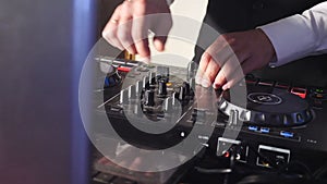 DJ behind console, on stage, mixing tracks in atmospheric dance party strobing and flashing lights. Close up of DJ hands