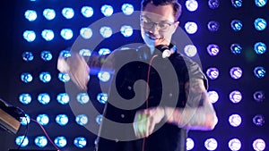 A DJ in black-rimmed glasses dances to the music.