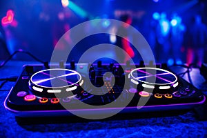 DJ console for mixing music with blurry people dancing at a nightclub party