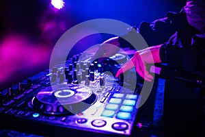 DJ console for mixing music with hands and with blurred people dancing at a night club party