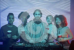 DJ with diverse group of people taking photo in nightclub