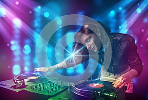 Dj girl mixing music in a club with blue and purple lights