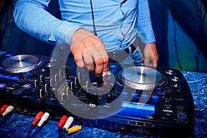 DJ hand controls volume and mix music in professional mixer in nightclub at party