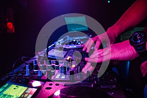 DJ hand mixes on a professional mixer in a nightclub
