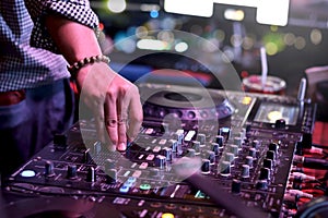 DJ hand playing live set and mixing music on controller turntable console mixing desk at stage in the night club, music beach