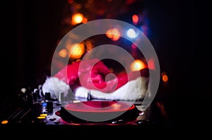 Dj mixer with headphones on dark nightclub background with Christmas tree New Year Eve. Close up view of New Year elements or symb