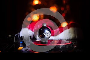 Dj mixer with headphones on dark nightclub background with Christmas tree New Year Eve. Close up view of New Year elements or symb