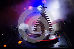 Dj mixer with headphones on dark nightclub background with Christmas tree New Year Eve. Close up view of New Year elements or symb