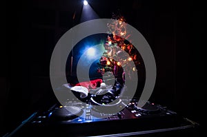 Dj mixer with headphones on dark nightclub background with Christmas tree New Year Eve. Close up view of New Year elements or symb