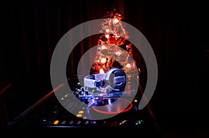 Dj mixer with headphones on dark nightclub background with Christmas tree New Year Eve. Close up view of New Year elements or symb