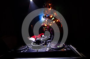 Dj mixer with headphones on dark nightclub background with Christmas tree New Year Eve. Close up view of New Year elements or symb
